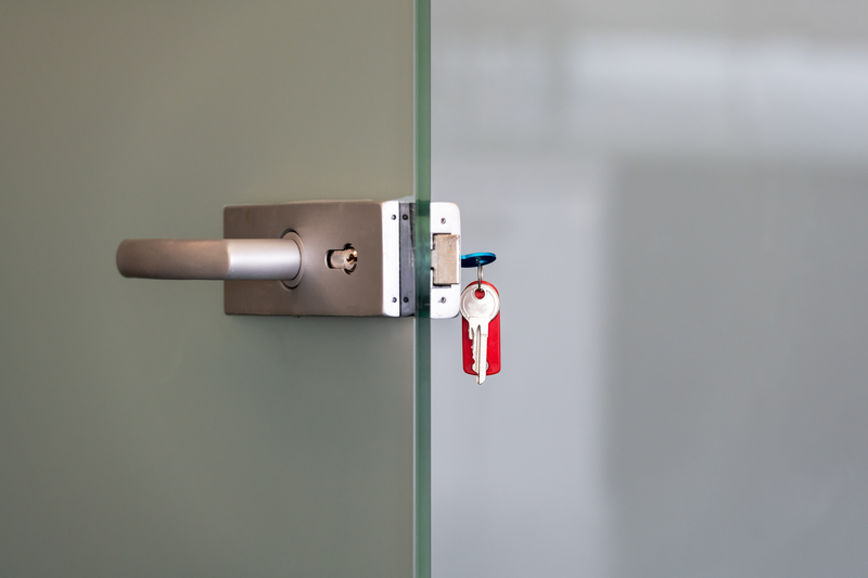 Modern glass door with metal alloy handles and key chain in lock, home or office security concept